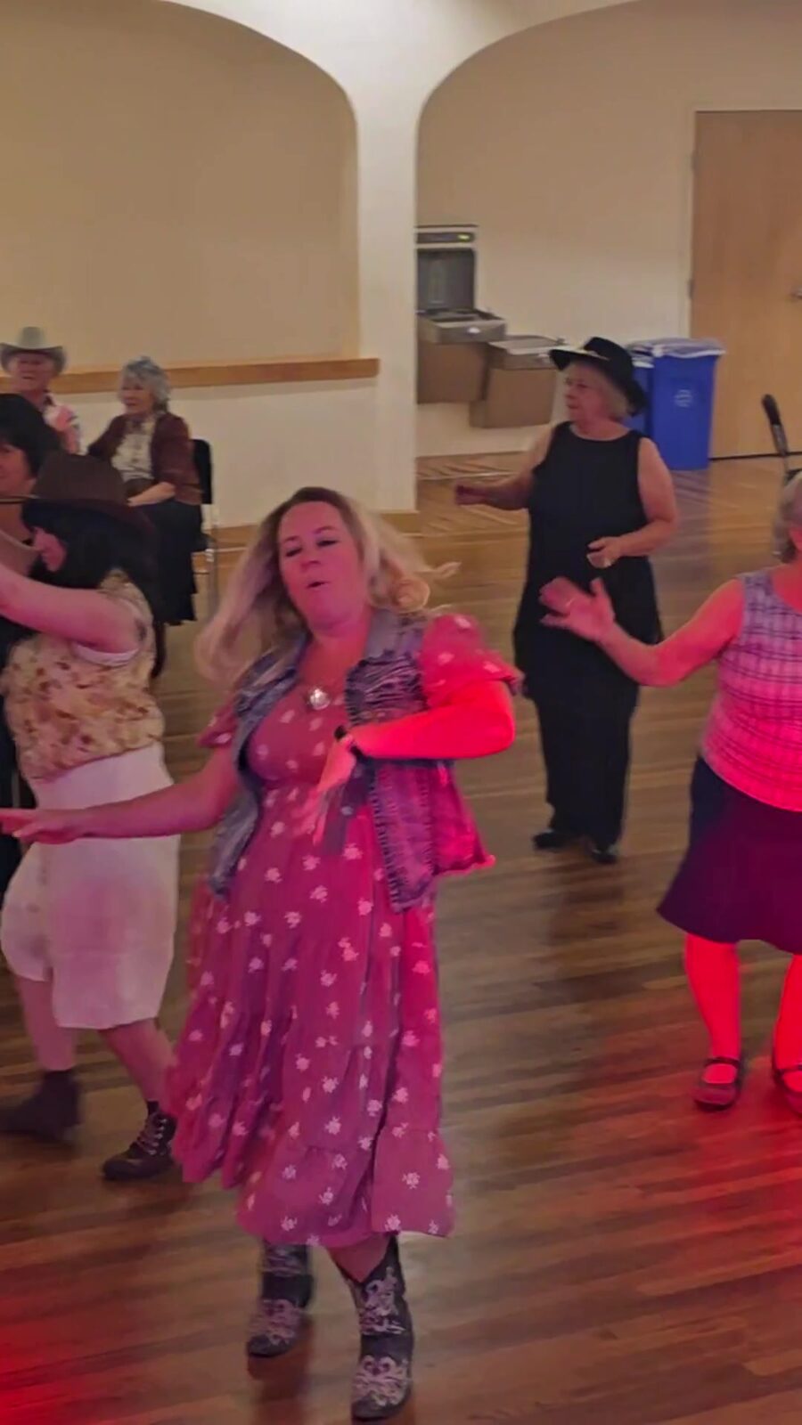 Guests line dancing between round tables at a 50th anniversary party